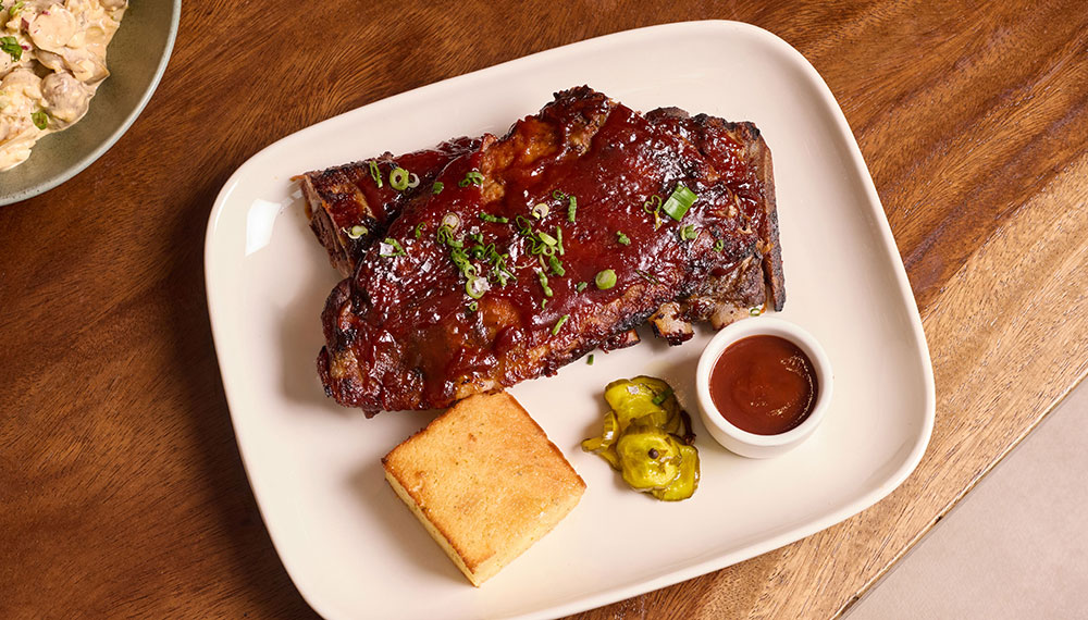 Ribs, cornbread, and barbque sauce on a plate